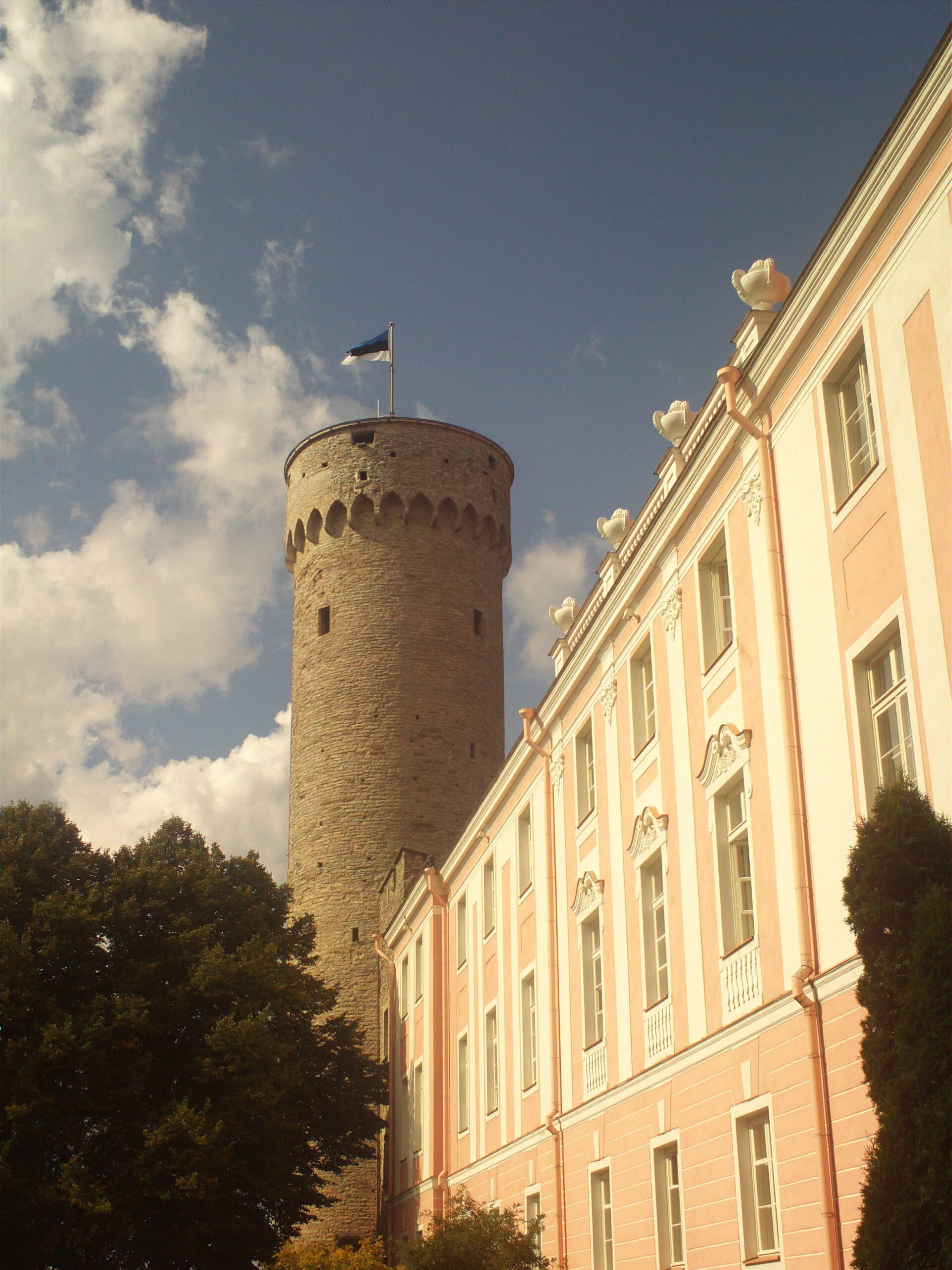 The Pikk Hermann (Tall Hermann) tower at Toompea Castle in Tallinn, with the Estonian flag flying from the top and the Riigikogu parliament building beside it.