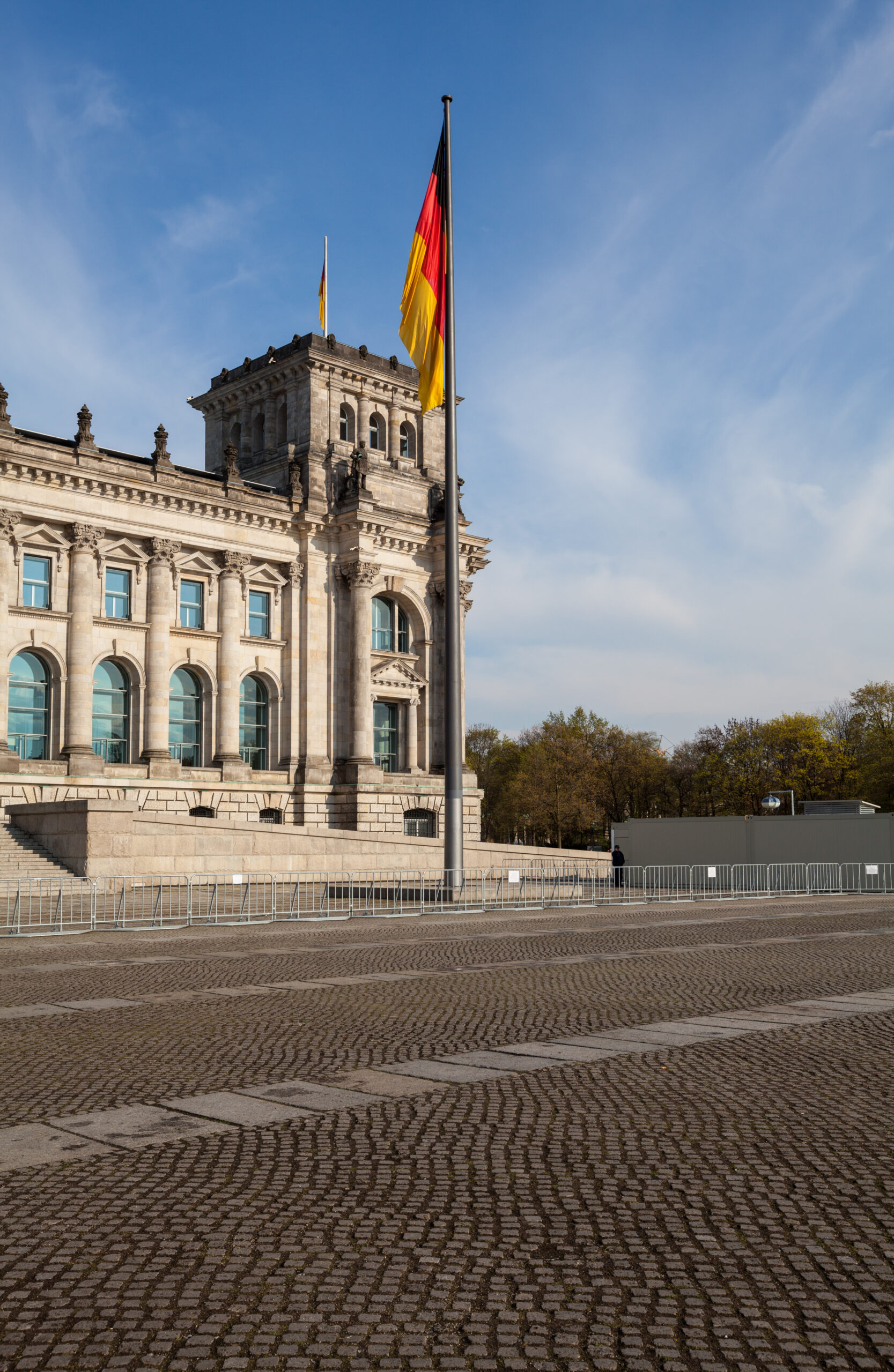 The southwest tower of the Reichstag building in Berlin with the German federal flag (Bundesflagge) on a flagpole in the foreground.