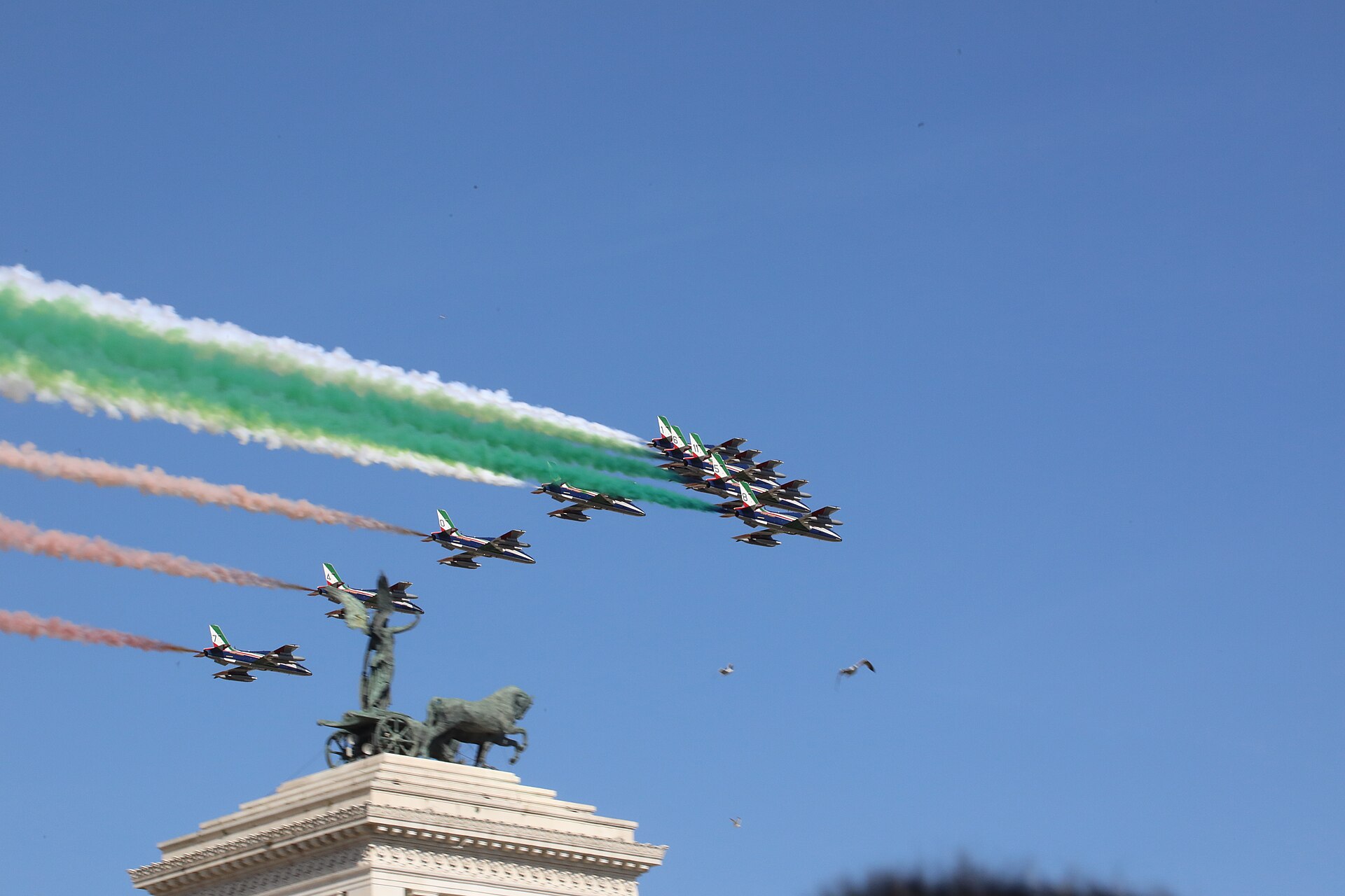 The nine Aermacchi MB-339 jets of the Frecce Tricolori in arrowhead formation, trailing distinct green, white and red smoke directly over the bronze quadriga atop the Vittoriano monument in Rome, during the 2 June 2018 Republic Day flyover.